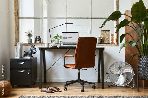 Creative composition of modern masculine home office workspace interior design with black industrial desk, brown leather armchair, laptop and stylish personal accessories. Template.