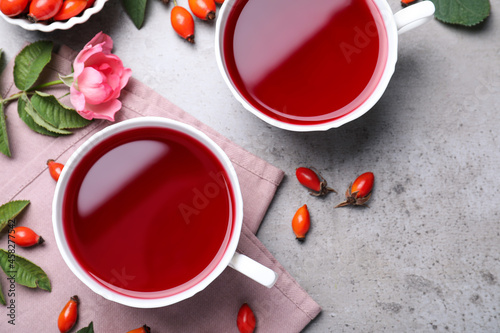 Fresh rose hip tea and berries on grey table, flat lay