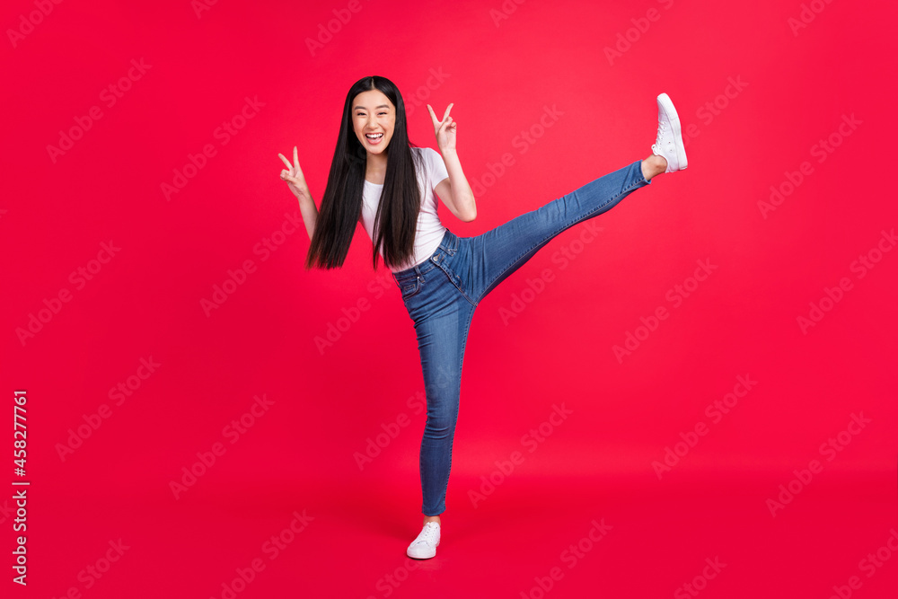 Full body photo of young attractive asian girl happy positive smile show peace cool v-sign isolated over red color background