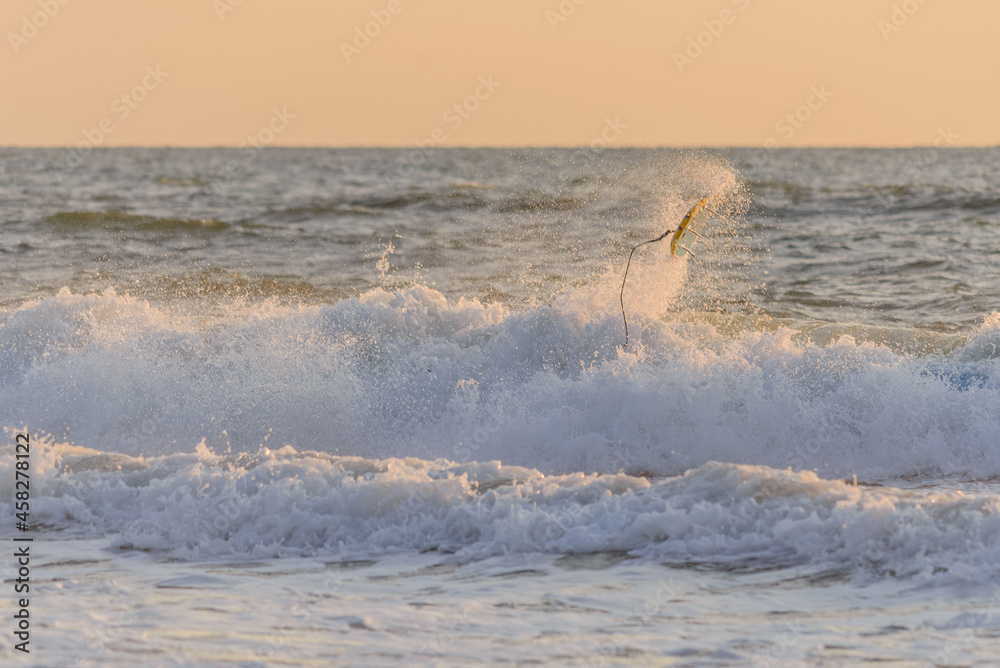 Fototapeta premium surfboard flying through the air after a surfer crashed mid wave during a beautiful sunset surf session.