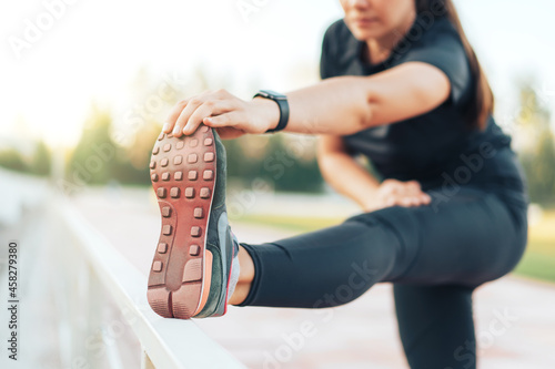 Girl in sportswear doing leg stretching in sports stadium