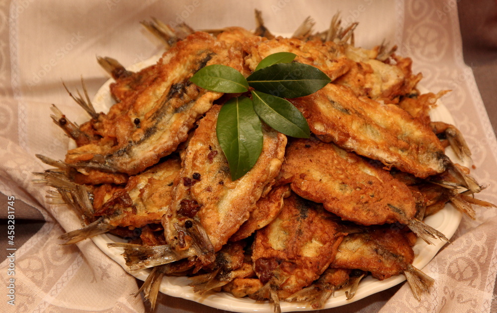 Crispy deep fried small fish on a plate, decorated with bay leaves and spices. Dough herring. Herring recipes Crispy deep fried small fish on a plate, decorated with bay leaves and spices. Dough herring. Herring recipes