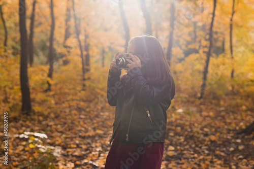 A little girl take a photo with old retro camera in autumn nature. Leisure and hobby concept.