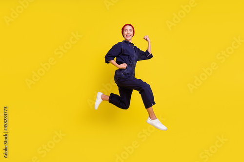 Full size photo of young beautiful smiling woman running fast speed in air wear red beanie isolated on yellow color background © deagreez
