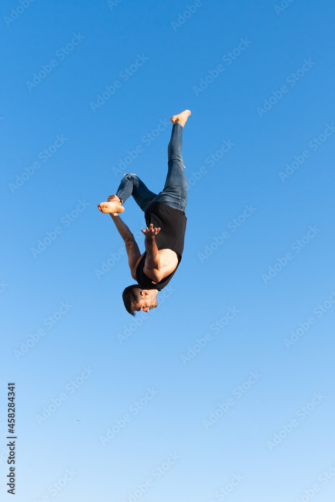 Energetic dancer performing trick in mid air above palm trees Energetic dancer performing trick in mid air above palm trees