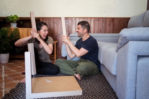 Happy multiethnic couple having fun with table legs at home photo