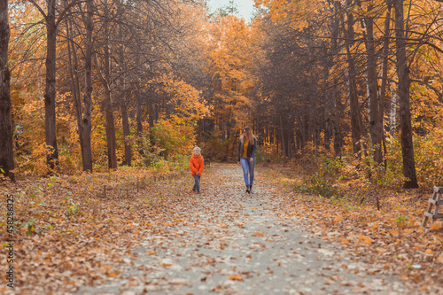 Mother and son walking in the fall park and enjoying the beautiful autumn nature. Season, single parent and children concept. © satura_