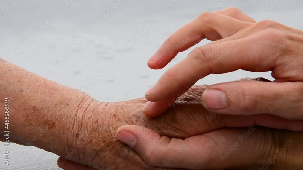 A young hand touches an old hand. Thanks to the parents. Seniors concept. Old hands of the grandmother. Young and old hands in place. Support and care. Support. Kindness and mercy A young hand touches an old hand. Thanks to the parents. Seniors concept. Old hands of the grandmother. Young and old hands in place. Support and care. Support. Kindness and mercy