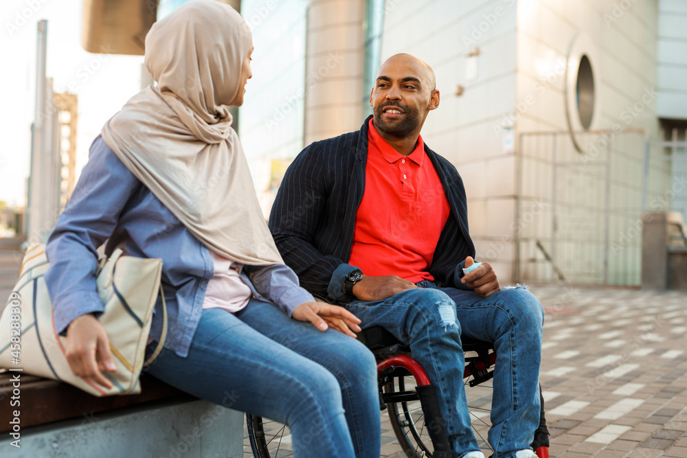 Muslim woman and disabled man talking to each other Muslim woman and disabled man talking to each other