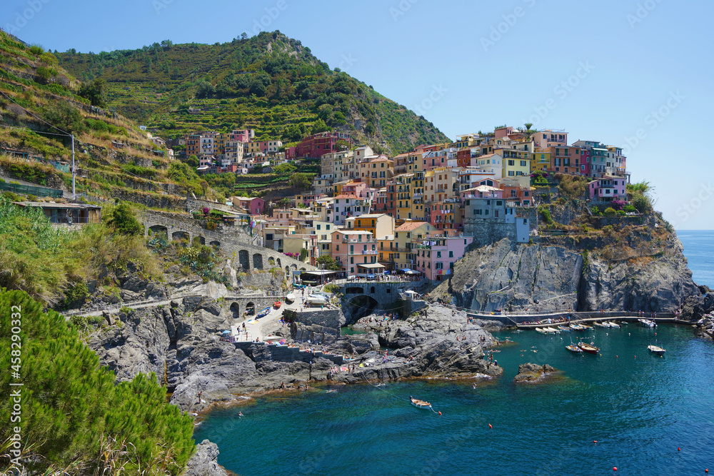 Manarola typical Italian village in the National Park of Cinque Terre with colorful houses on rock cliff, fishing boats on water, Liguria, Italy