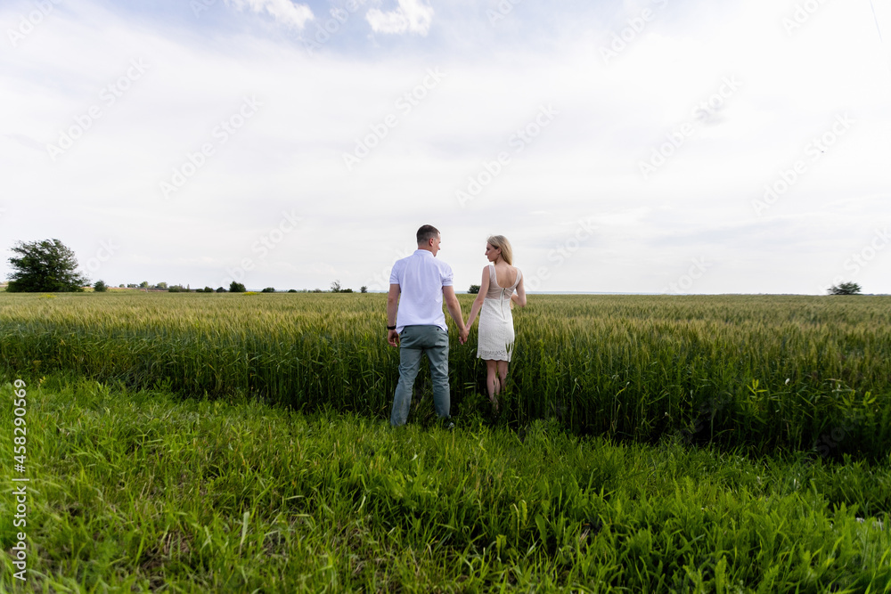 Young couple in the wheat field on sunny summer day. Couple in love have fun in golden field.