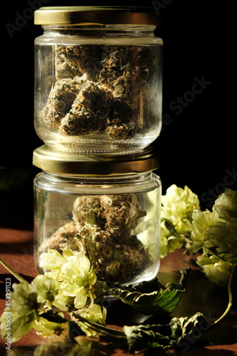 Cannabis drying and curing. Macro view, close up. Marijuana buds in glass jars and hop branch. Eco container. Hemp growing concept.