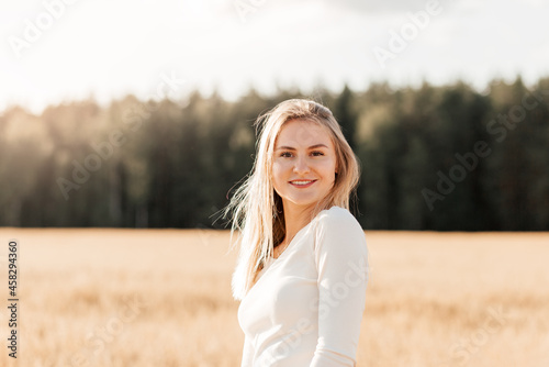 A young beautiful girl in a denim skirt walks through a wheat field on a sunny day