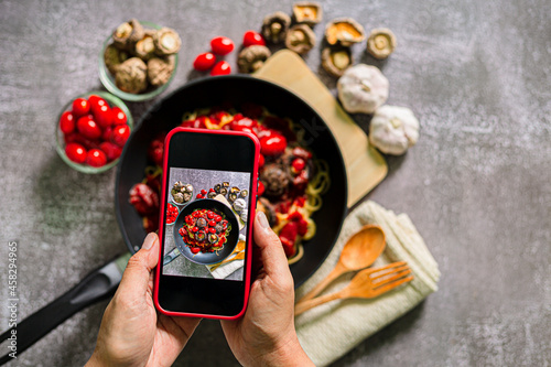 Take a photo of spaghetti with a mobile phone,Top view of woman taking photo on dishes