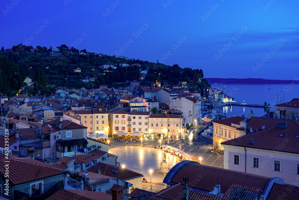Beautiful sunset in Piran with Tartini square at night with city lights