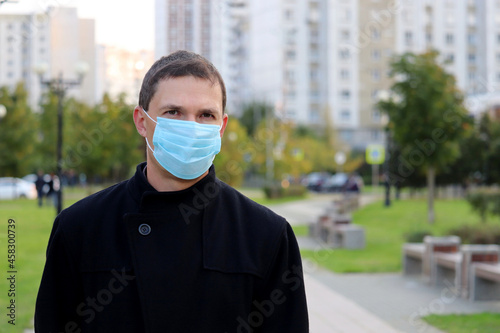 Coronavirus protection at autumn, man in disposable face mask on a city street