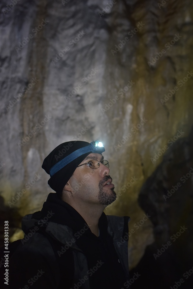 Male hiker exploring a dark cave.Travel destination in Slovakia Male hiker exploring a dark cave.Travel destination in Slovakia