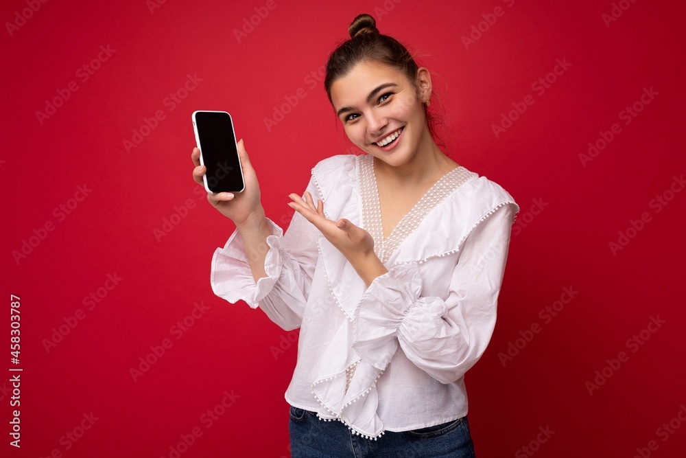 Photo of beautiful smiling young woman good looking wearing casual stylish outfit standing isolated on background with copy space holding smartphone showing phone in hand with empty screen display for Photo of beautiful smiling young woman good looking wearing casual stylish outfit standing isolated on background with copy space holding smartphone showing phone in hand with empty screen display for