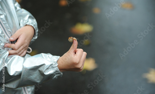Child holding a little snail in hand outdoors © Alona