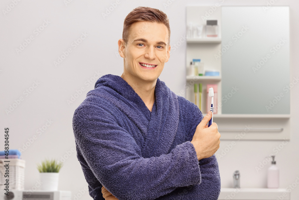 Young man in a bathrobe holding a toothbrush Young man in a bathrobe holding a toothbrush