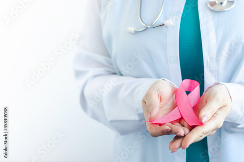 Breast Cancer Awareness Month. Female doctor in medical white uniform holds pink ribbon in her hands. Womens health care