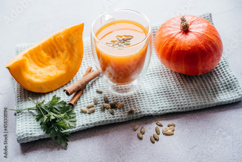 A glass of fresh pumpkin smoothie decorated with a leaf of parsley