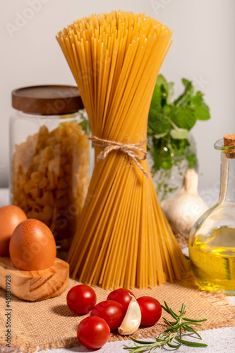 Pasta and its ingredients on a bright background. Copy space.