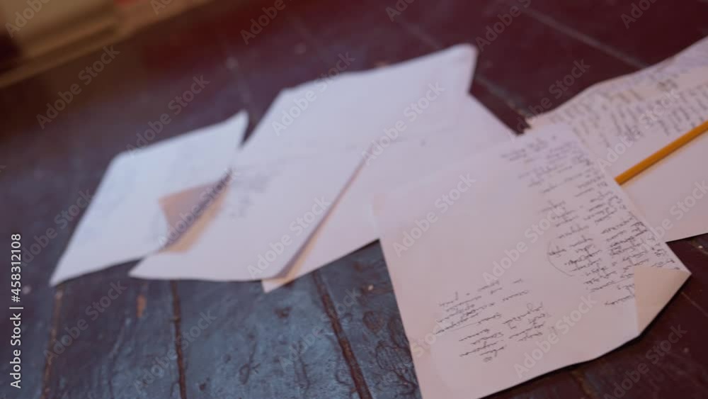 Scribbled on A4 paper, sheets lie on the old wooden floor.