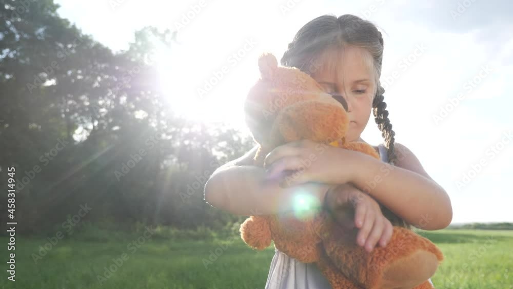 little kid girl hugging a teddy bear toy portrait in the park in nature ...