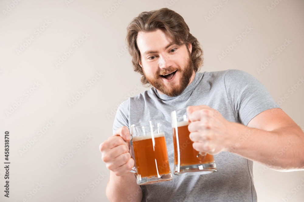Portrait of a happy young bearded man holding two beer mugs isolated over light gray background Portrait of a happy young bearded man holding two beer mugs isolated over light gray background