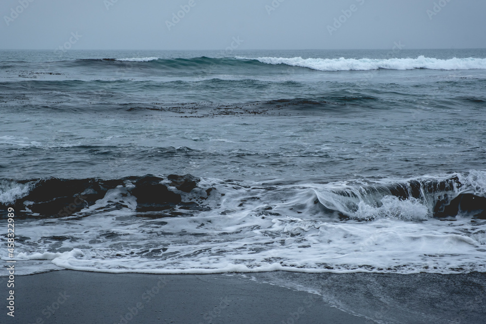 Fototapeta premium Panoramic view of the pacific ocean with waves, the horizon with cloudy sky and the shore and beach