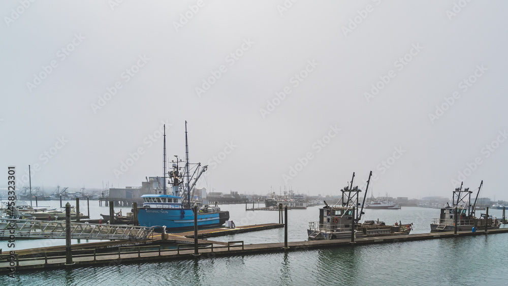 Fishing trawlers at dock in foggy weather in a marina