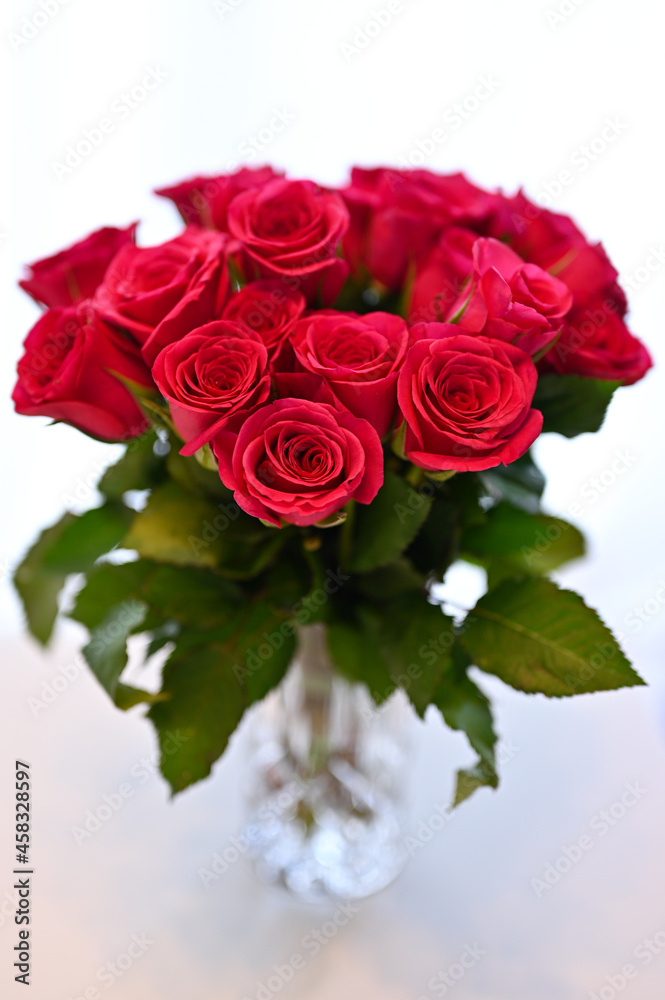 Obraz premium Pink roter Rosenstrauß vor hellem weißen Hintergrund in einer Vasea