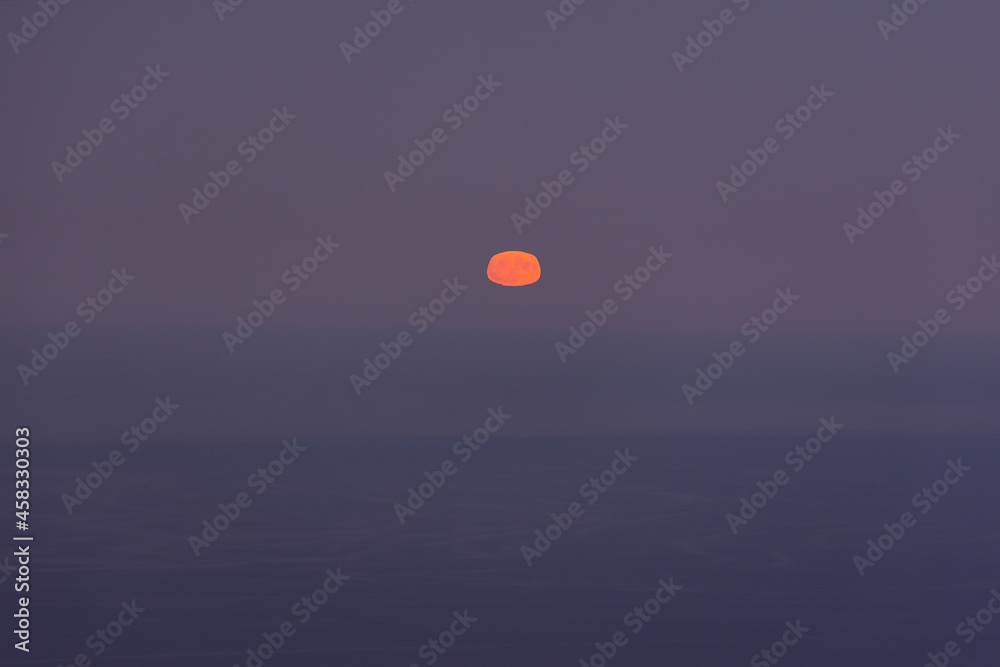 Full moon sea. The supermoon is orange in a purple sky over the ocean. Horizontal minimalistic natural night background. A mystical landscape with a rising yellow moon. Mysterious Halloween background Full moon sea. The supermoon is orange in a purple sky over the ocean. Horizontal minimalistic natural night background. A mystical landscape with a rising yellow moon. Mysterious Halloween background