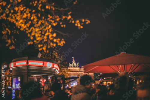 Fototapeta Naklejka Na Ścianę i Meble -  Il festival delle luci di Berlino, mix di colori caldi nel immersi nel nero del buio della notte. Porta di Brandeburgo + antenna della televisione di Alexanderplatz.