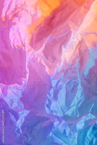 Abstract background with crumpled paper in neon gradient. Vivid blue  pink and orange colors
