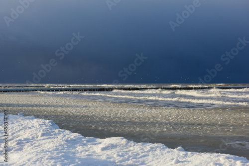 Morski krajobraz zimowy. Woda morska przy bardzo niskiej temperaturze staje się mieszaniną lodu i wody. Ciemne chmury zwiastujące nadchodzący sztorm.