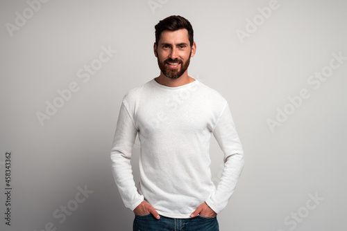Portrait of happy smiley bearded man with white shirt against light gray background and smiling to the camera. Studio shot. People emotions concept
