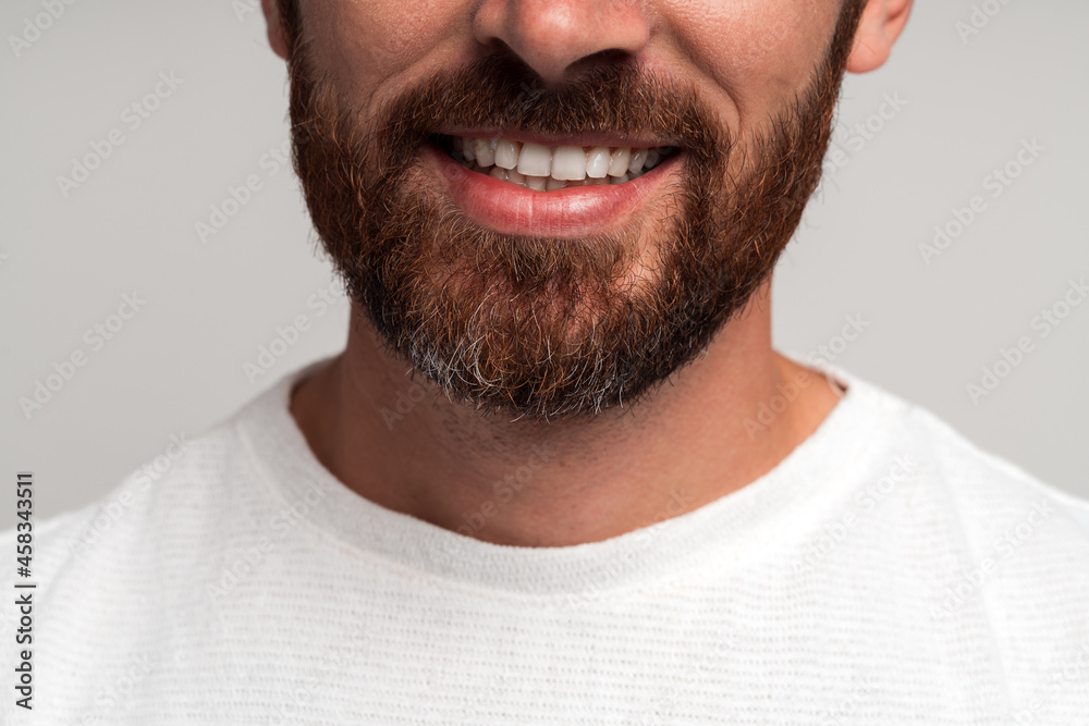 Obraz premium Close up portrait of happy handsome bearded businessman standing and smiling. Indoor studio shot, isolated on light grey background