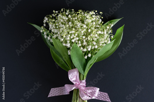 Happy holiday concept. A bouquet of beautiful fragrant white lilies of the valley on a dark background.