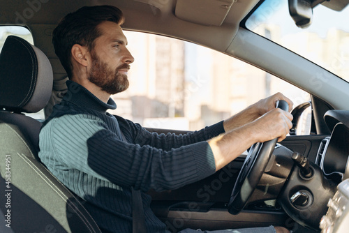 Side view of the serious confident man riding at the car and feeling confident while looking at the road during driving. Stock photo