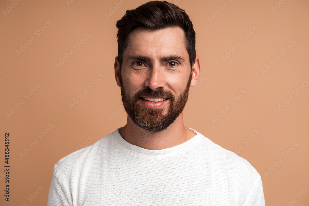 Portrait of cheerful handsome man in white shirt looking at camera, feeling joyfully as if having interesting idea. Studio shot isolated on beige background Portrait of cheerful handsome man in white shirt looking at camera, feeling joyfully as if having interesting idea. Studio shot isolated on beige background