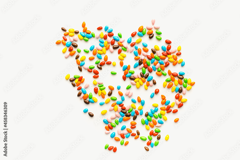 Colored dragee on a white background. Bright candies. Seeds in glaze. Colored background.