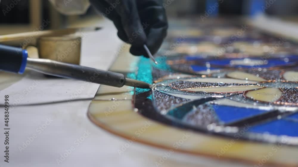 Closeup Soldering stained glass seams. Gloved hands with a soldering