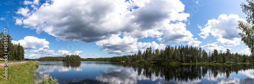travel sweden and scandinavia, beautiful lake covered with trees and blue sky and white clouds above