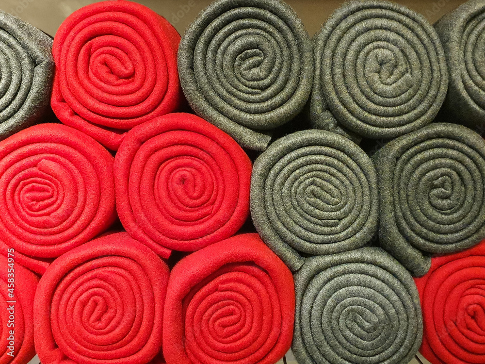 Stack of red and grey blankets rolled on a shelve as background 