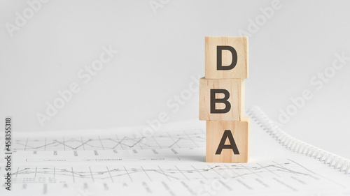 three stone cubes on the background of white financial statements, tables with the word DBA. Strong business concept