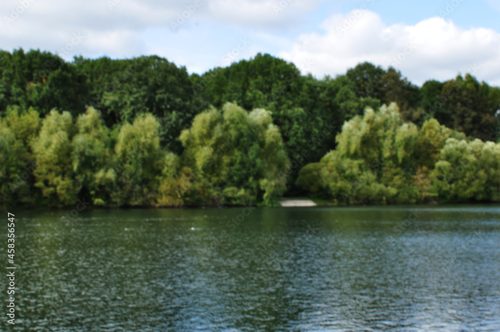 Blurred lake panorama background. Without focus, the water surface of the lake and the trees on the shore. Blurred lake panorama background. Without focus, the water surface of the lake and the trees on the shore.