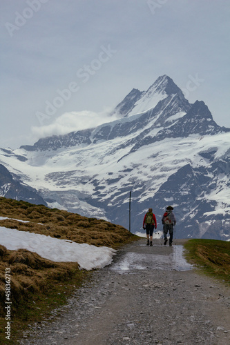 Backpacker hiker walking on panoramic trail with view on swiss alps with snow
