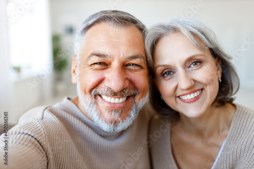 Portrait of happy beautiful senior caucasian couple smiling at camera while making selfie